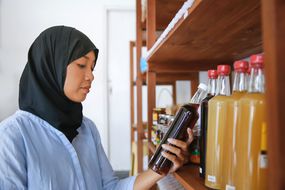 印度尼西亚穆斯林妇女在有机商店的架子上检查蜂蜜上的标签