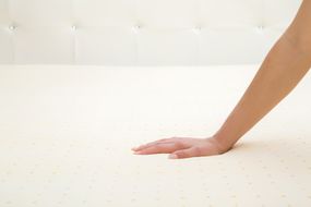 Hand pressing down on a mattress