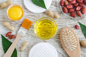 Small glass bowl with peanut (groundnut) oil and raw egg yolk. Natural face and hair mask recipe. Ingredients of homemade cosmetics. Top view, copy space.