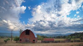 small homestead with classic red barn and brilliant blue sky with clouds