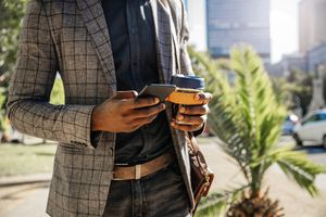 商人发短信和拿着一杯咖啡的中央部位