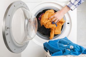 人们用手把脏衣服放进洗衣机里