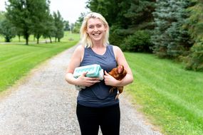 woman smiles while holding egg carton and chicken