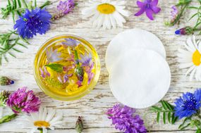 小玻璃碗香气化妆品石油用鲜花提取棉花垫。天然护肤品和自制化妆品的概念。”width=