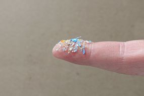 近距离拍摄的塑料微粒对人类的手指。