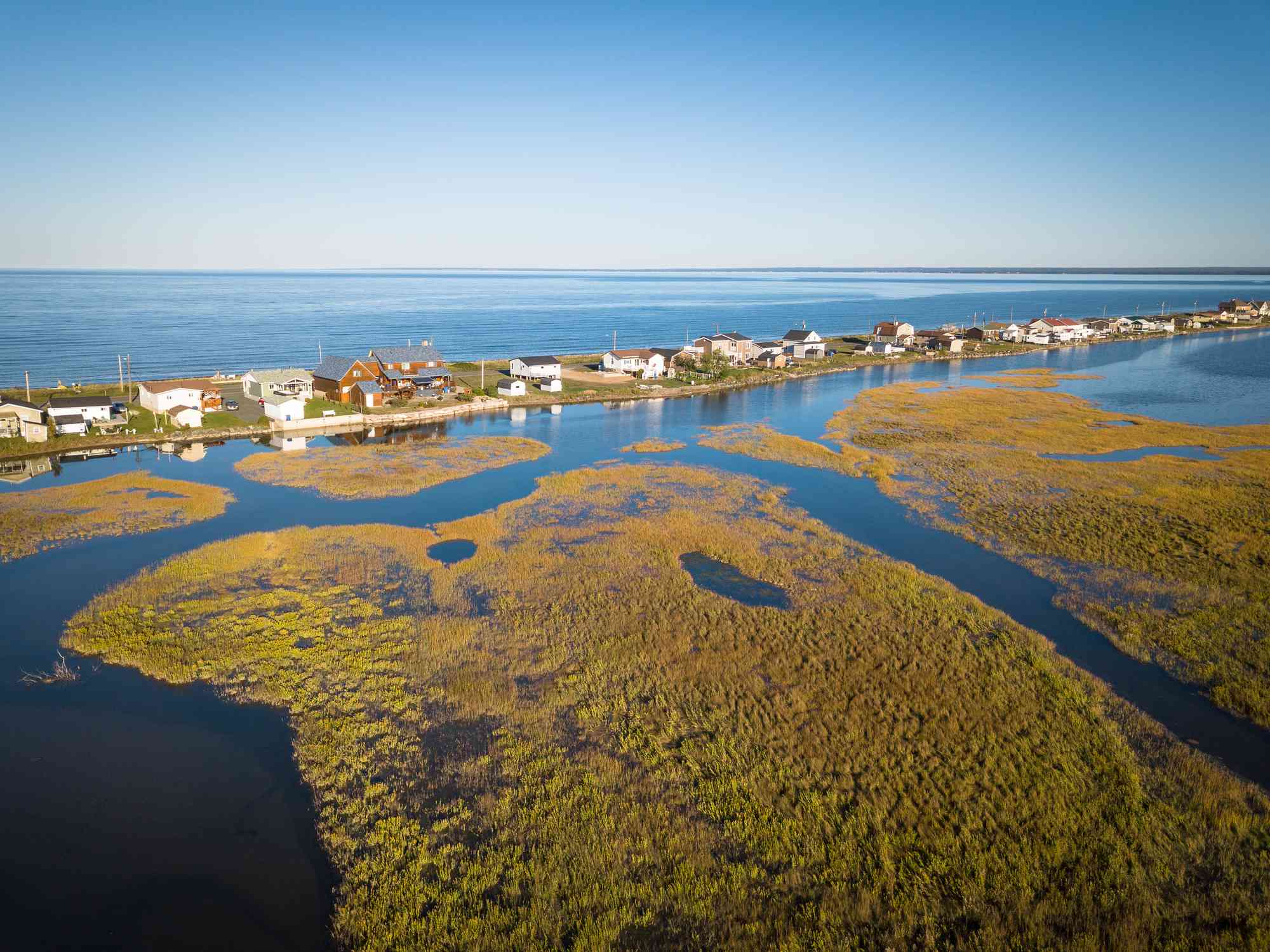 Cottages along a sandbar backed by salt marshes. Beresford, New Brunswick, Canada