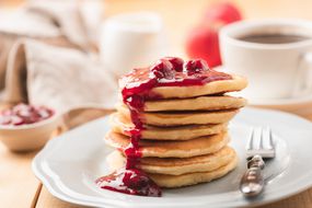 Closeup view of pancakes with berry sauce and coffee breakfast.