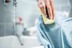 一个女人正在用海绵清洗沾污的衬衫