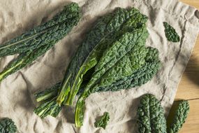 Raw kale leaves on a beige cloth on wooden surface