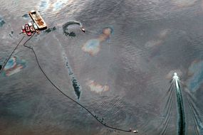 Aerial view of oil-covered water being skimmed by small boat following Exxon Valdez oil spill