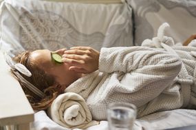 女人用冷的黄瓜片放在沙发上，以使眼睛下方的黑眼圈