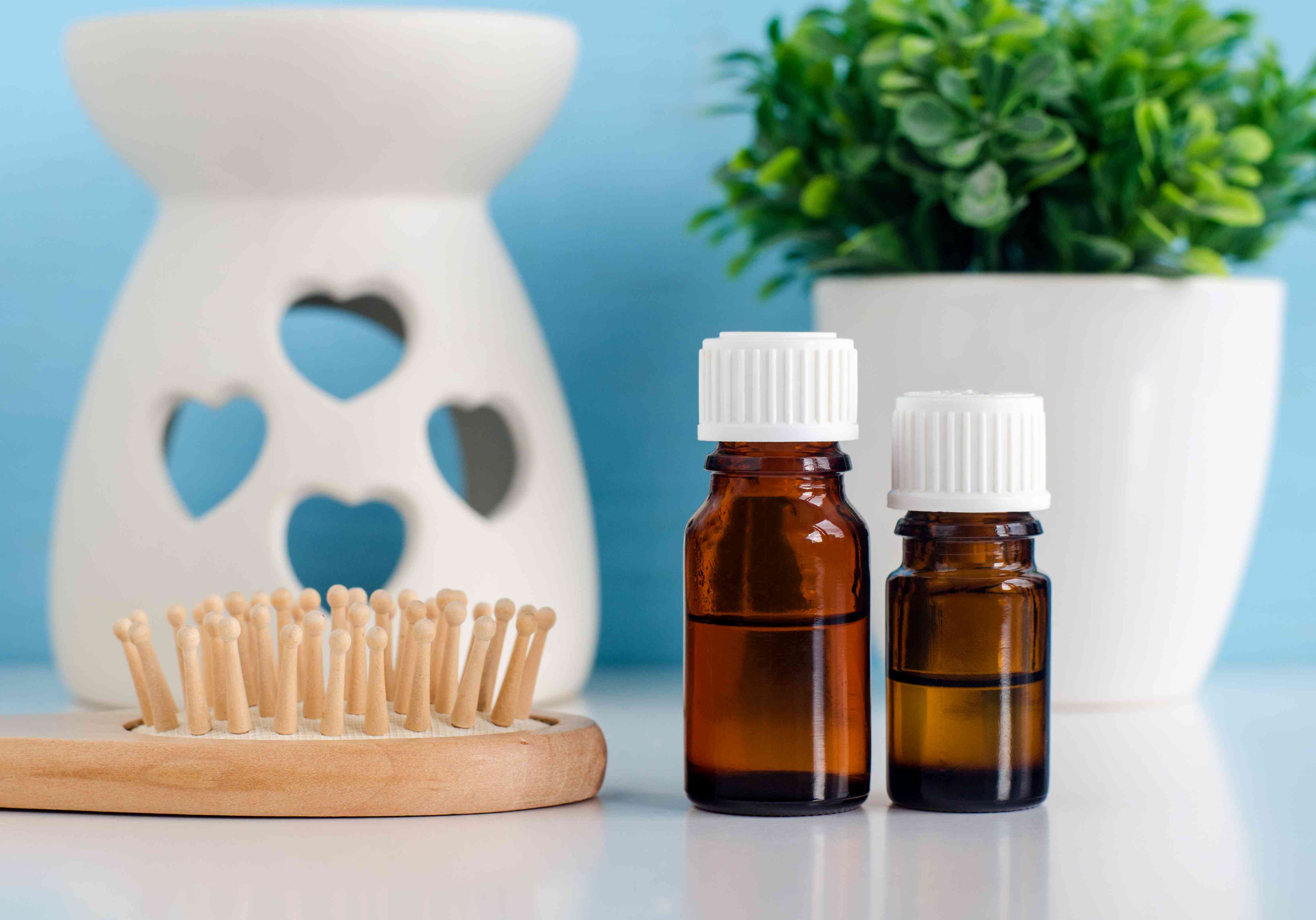 Two small glass bottles with essential oil and wooden hair brush. Aromatherapy, spa and herbal medicine ingredients. Copy space.