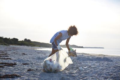 从海滩上收集垃圾并把它装进袋子里的人