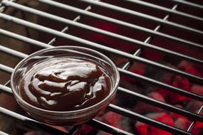 Bowl of BBQ sauce on a grill